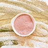 Arena de spa natural rosada en cuenco, evocando la arcilla rosada para mascarillas faciales