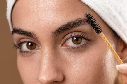 Mujer peinando sus cejas con un cepillo para cejas de bambú en su rutina – Izana Naturals